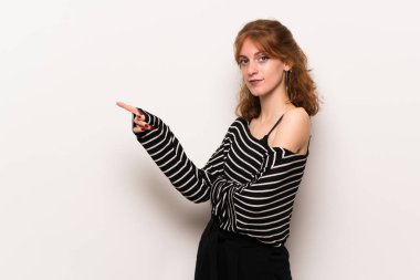 Beyaz duvar işaret parmağı lateral pozisyonda Side'ye genç Kızıl saçlı kadın