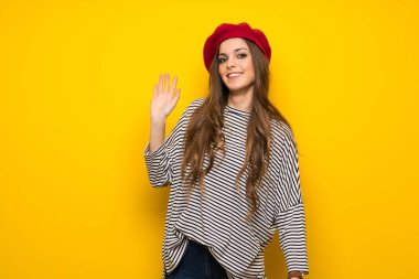 Kızla Fransız tarzı mutlu ifade ile el ile sarı duvar selamlayan üzerinde