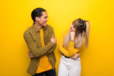 Canlı sarı arka plan üzerinde genç çift tatlı bir ifade ile gülümseyerek
