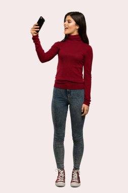 Bir selfie izole arka plan üzerinde yapım balıkçı yaka bir genç kızla tam uzunlukta bir kadeh