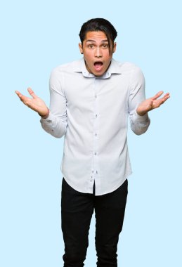 Izole mavi arka plan üzerinde sürpriz ve şok yüz ifadesi ile Yakışıklı adam