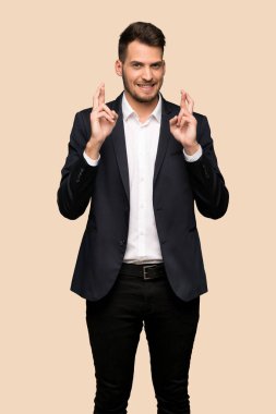 Yakışıklı iş adamı ile koyu sarı arka plan üzerinde en iyi dilek ve geçiş parmak