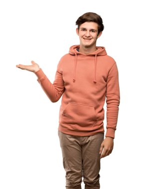 Genç adam boşaltmak hayali avuç içinde tutarak kazak ile izole beyaz arka plan üzerinde bir reklam eklemek için