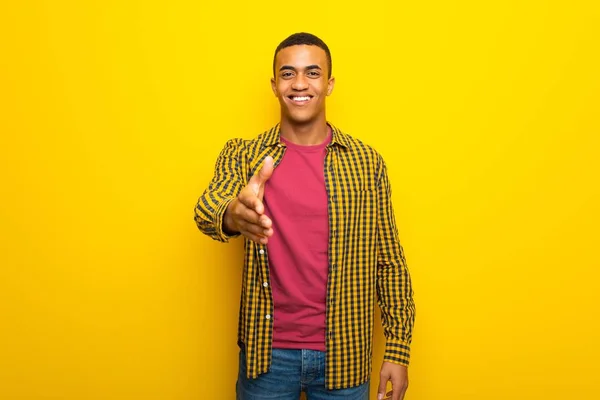 良い取引を閉じるため握手黄色背景に若いアフロ アメリカ人 — ストック写真