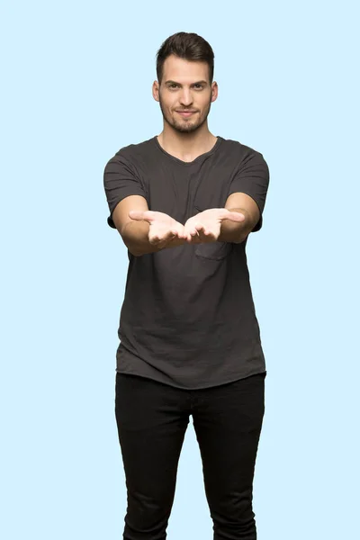 Man Black Shirt Holding Copyspace Imaginary Palm Insert Blue Background — Stock Photo, Image