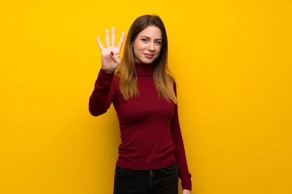 Donna Con Dolcevita Sul Muro Giallo Felice Contando Quattro Con — Foto Stock