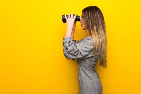 Sarı Duvar Uzaktan Dürbünle Bakarak Gözlüklü Genç Kadın — Stok fotoğraf