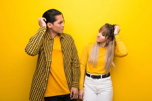 Canlı sarı arka plan üzerinde genç çift baş çizilme sırasında şüpheler sahip