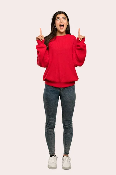 孤立した背景にびっくり赤いセーターが指していると 代の女の子のフルレングス ショット — ストック写真