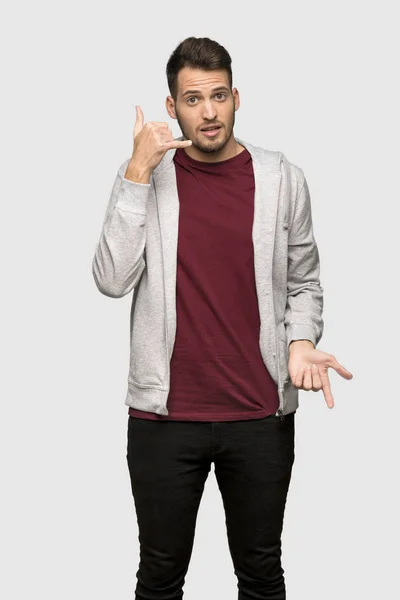電話のジェスチャーを作る 灰色の背景の上のスエット シャツを持つ男 — ストック写真