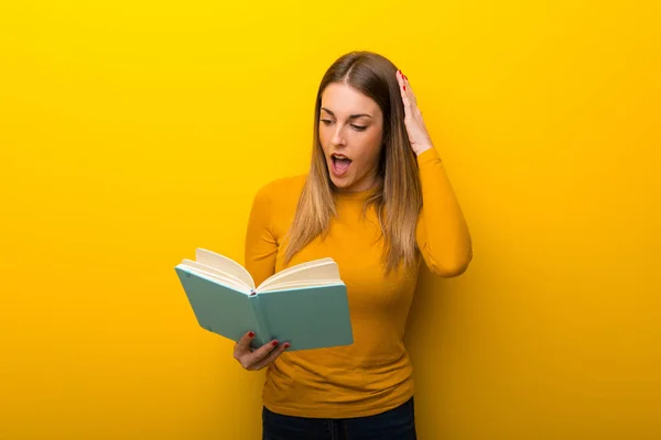 Junge Frau Auf Gelbem Hintergrund Überrascht Beim Lesen Eines Buches — Stockfoto