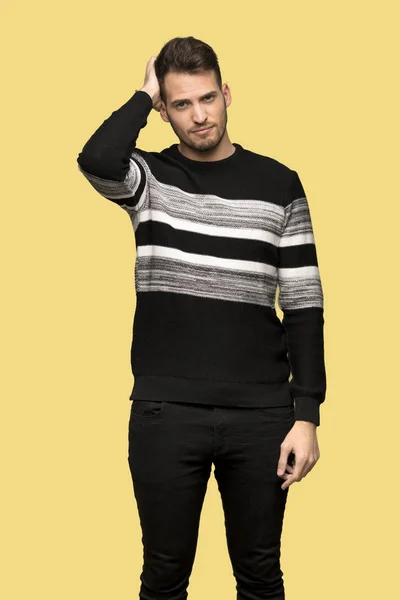 Handsome man with an expression of frustration and not understanding over yellow background