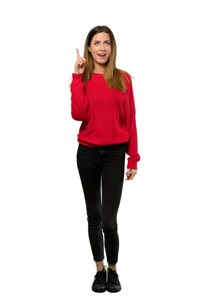 分離の白い背景の上指を指してアイデアを考えて赤いセーターを持つ若い女性のフルレングス ショット — ストック写真
