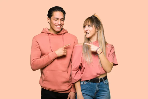 Junges Paar Zeigt Zur Seite Ein Produkt Auf Rosa Hintergrund — Stockfoto