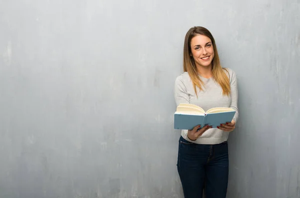 Junge Frau Strukturierter Wand Hält Ein Buch Und Gibt Jemandem — Stockfoto