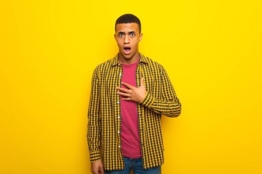 Genç afro Amerikalı adam şaşırttı ve doğru bakarken şok sarı zemin üzerine
