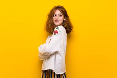 Sarı duvar bir gülümseme ile omuz üzerinden arıyor genç Kızıl saçlı kadın