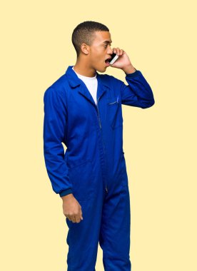 Genç afro Amerikan işçi adam cep telefonu ile bir görüşme izole arka plan üzerinde tutulması