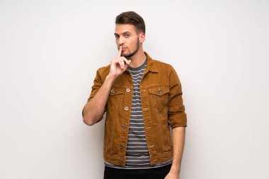 Beyaz duvar bir işaret parmağını ağzına koyarak sessizlik jest gösteren yakışıklı adam