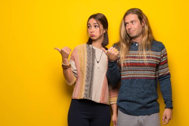 Hippi çift üzerinde sarı arka plan mutsuz ve tarafa işaretleme