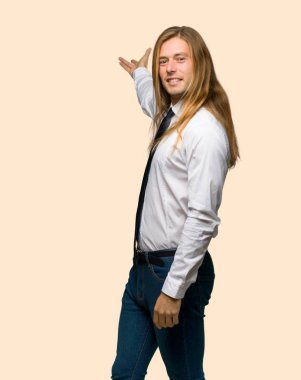 Geri işaret ve bir ürün yalıtılmış zemin üzerine sunma uzun saçlı sarışın iş adamı