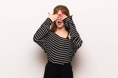 Beyaz duvar eller tarafından gözleri kaplama genç Kızıl saçlı kadın. İleride ne olduğunu görmek için sürpriz