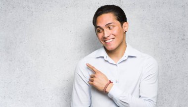 Yakışıklı adam dokulu duvar arka plan üzerinde bir ürün sunmak için yan işaret