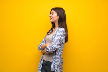 Sarı duvar mutlu ve gülümseyen genç kız