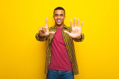 Yedi parmak ile sayma Sarı zemin üzerine genç afro Amerikalı adam