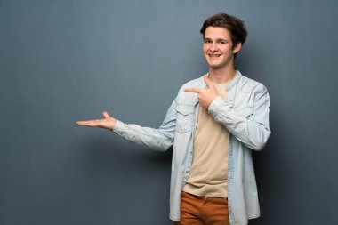 Jean ceket gri duvarın boşaltmak hayali avuç içinde holding üzerinden olan genç adam bir reklam eklemek için