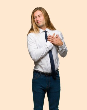 İzole arka plan üzerinde kalbinde bir ağrısı olan uzun saçlı sarışın iş adamı