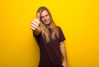 Çünkü iyi bir şey oldu bir başparmak yukarıya hareket veren sarı duvarın üzerinden uzun saçlı sarışın adam