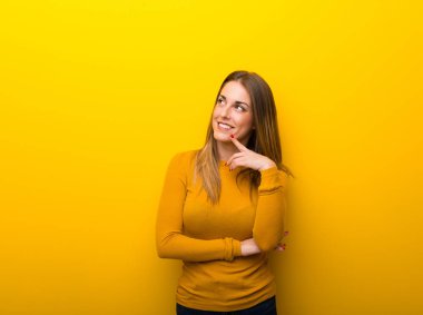 Genç kadın bir fikir ararken süre düşünme Sarı zemin üzerine