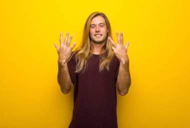 Dokuz parmaklı sayma sarı duvarın üzerinden uzun saçlı sarışın adam
