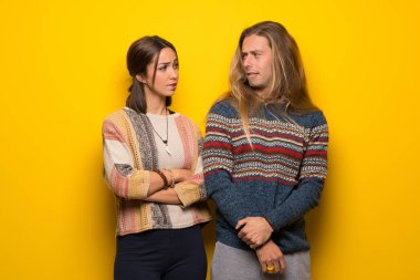 Hippi çift sarı arka plan ile karıştırmayın yüz ifadesi sırasında ısırıkları dudak üzerinde