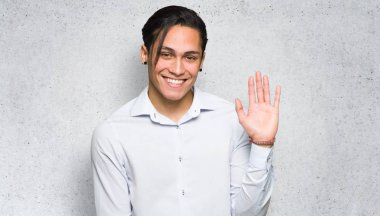 Dokulu duvar arka plan üzerinde mutlu ifade ile el ile selamlama Yakışıklı adam