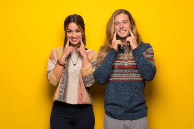 Hippi çift mutlu ve keyifli bir ifadeyle gülümseyen sarı arka plan üzerinde