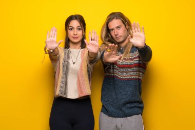 Hippi çift dur jest yapmak için sarı arka plan üzerinde bir görüş ile hayal kırıklığına