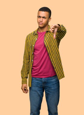 Başparmak aşağı işareti ile negatif ifade izole arka plan üzerinde gösterilen genç afro Amerikalı adam