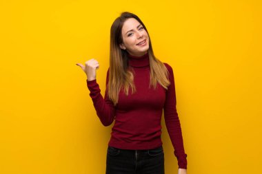 Ürün sunmak için balıkçı yaka üzerine sarı duvar tarafına işaret kadınla