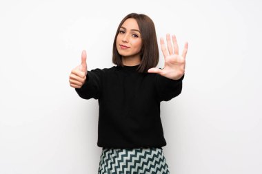 Beyaz duvar altı parmak ile sayma genç kadın