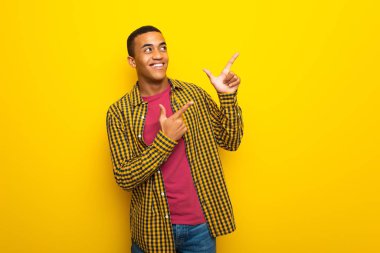 İşaret parmağı ile işaret ve ararken Sarı zemin üzerine genç afro Amerikalı adam