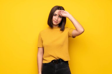 Yorgun ve hasta ifade ile sarı duvarın üzerinden genç kadın