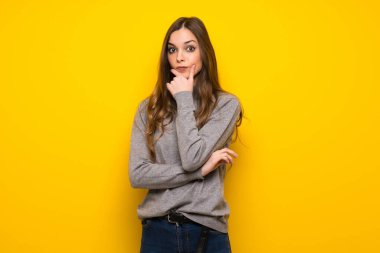 Genç kadın gülümseyerek ve öne doğru emin yüz ile seyir sarı duvarın üzerinden