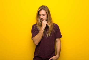 Çene üzerinde el ile bakıyordu sarı duvarın üzerinden uzun saçlı sarışın adam