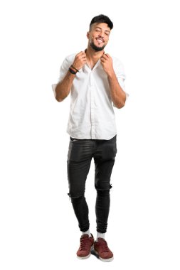 Beyaz tişörtlü, beyaz gömlekli, kendini beğenmiş, kendini beğenmiş, soyutlanmış beyaz arka plan konsepti olan Arap bir gencin uzun bir resmi.