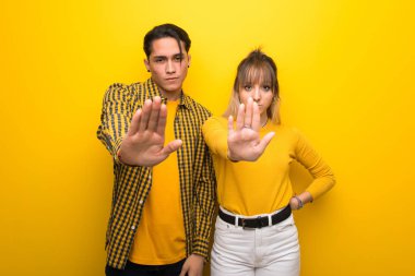 Canlı sarı arka plan üzerinde genç çift yanlış düşünen bir durum inkar jest durdurmak yapma