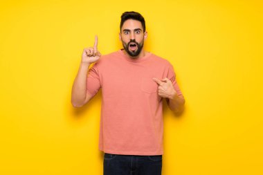 Sürpriz yüz ifadesi ile sarı duvarın üzerinden yakışıklı adam