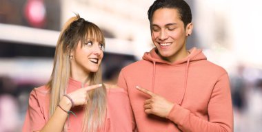 Genç çift şehirde bir ürün sunmak için yan işaret