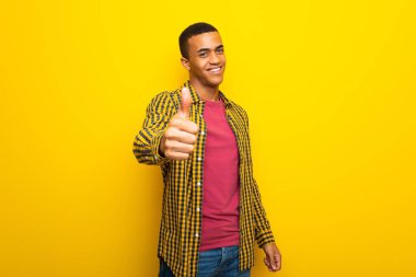 Çünkü iyi bir şey oldu bir başparmak yukarıya hareket veren Sarı zemin üzerine genç afro Amerikalı adam